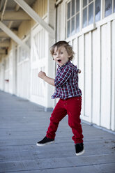 Porträt eines süßen Jungen, der auf der Veranda in die Luft springt - ISF01865