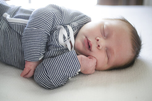 Süßes Baby mit Hand auf Kinn schlafend auf Bett - ISF01886
