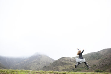 Landscape view of girl in tutu jumping mid air - ISF01887