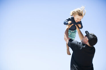 Father and son fooling around outdoors, father lifting son in air - ISF01900