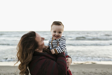 Mother on beach holding smiling baby boy - ISF01933
