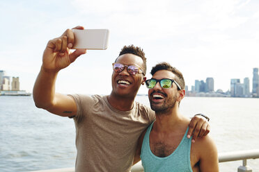 Two young men taking smartphone selfie on waterfront, New York, USA - ISF01945