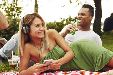 Frau wählt beim Picknick im Park die Musik ihres Smartphones - ISF01957