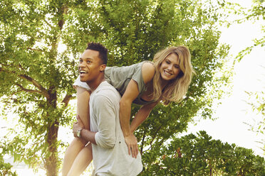 Junger Mann trägt seine Freundin über der Schulter in einem Park - ISF01968