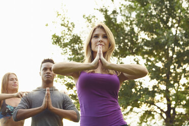 Männliche und weibliche Erwachsene üben Yoga mit zusammengelegten Händen im Park - ISF01973