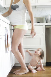 Kleines Mädchen auf dem Küchenboden von schwangerer Mutter - ISF02001