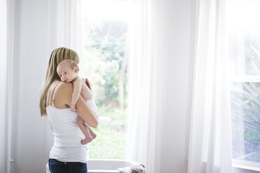 Mid adult woman carrying baby son in living room - ISF02005