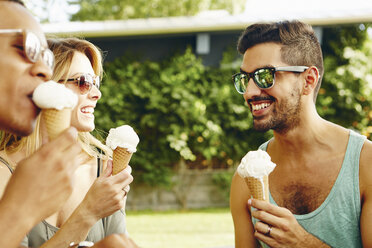 Male and female friends eating ice cream cones in park - ISF02041