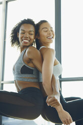 Zwei junge Frauen trainieren im Fitnessstudio, machen Kniebeugen, Rücken an Rücken - ISF02072