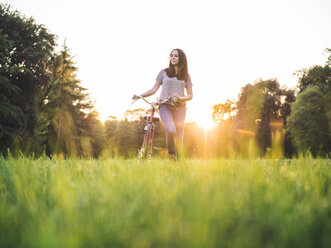 Frau geht mit dem Fahrrad auf dem Rasen - ISF02084