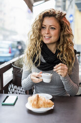 Woman in cafe holding espresso cup looking away smiling - CUF08237