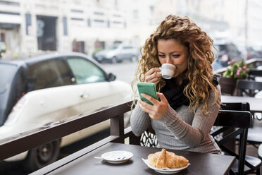 Frau in einem Café, die ein Smartphone benutzt, trinkt ein Café, Mailand, Italien - CUF08239