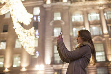 Junge Frau fotografiert Weihnachtsbeleuchtung, Regent Street, London, UK - CUF08247