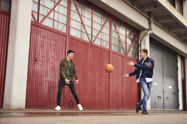 Zwei junge Männer spielen Basketball in einem städtischen Gebiet, Bristol, UK - CUF08372