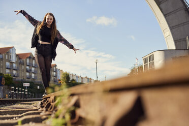 Junge Frau balanciert auf einem Zuggleis, Blickwinkel niedrig, Bristol, UK - CUF08381