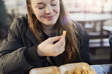 Porträt einer jungen Frau, die im Freien Chips isst, Bristol, UK - CUF08384