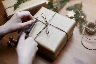 Woman tying bow on Christmas gift with string, close-up - CUF08400