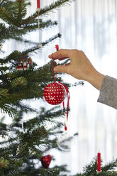 Senior woman putting bauble on christmas tree - CUF08406