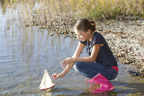 Junges Mädchen schwimmt mit Spielzeugboot auf dem Wasser - CUF08425