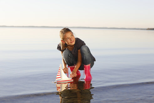 Junges Mädchen schwimmt mit Spielzeugboot auf dem Wasser - CUF08428