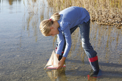 Junges Mädchen schwimmt mit Spielzeugboot auf dem Wasser - CUF08429