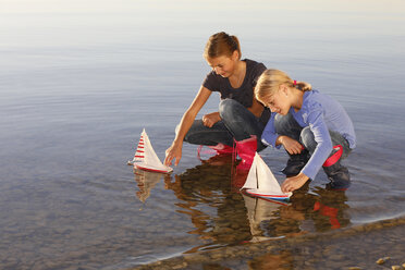 Zwei junge Mädchen schwimmen mit Spielzeugbooten auf dem Wasser - CUF08432