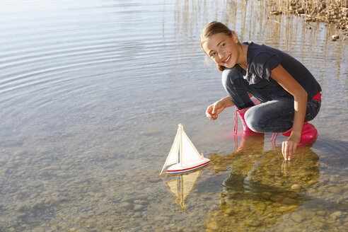 Junges Mädchen schwimmt mit Spielzeugboot auf dem Wasser - CUF08434