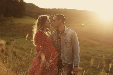 Romantische Mitte erwachsenen schwangeren Paar von Angesicht zu Angesicht auf einem Hügel bei Sonnenuntergang - CUF08452