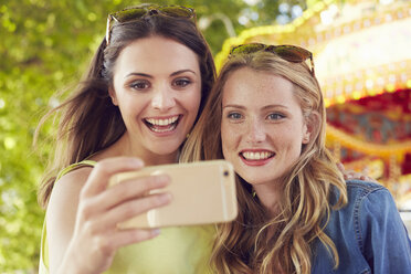 Women taking selfie, carousel in background, London, UK - CUF08483