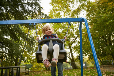 Father pushing daughter on playground swing - CUF08497