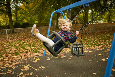 Girl swinging on playground swing - CUF08498