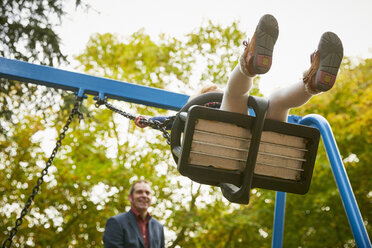 Father pushing daughter on playground swing - CUF08500