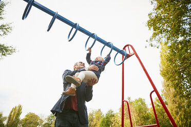 Father helping daughter on monkey bars in playground - CUF08503