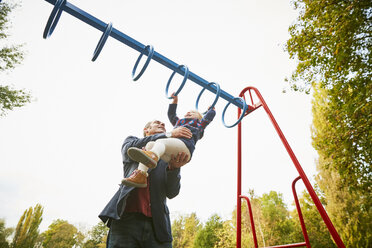 Vater hilft seiner Tochter auf dem Spielplatz auf dem Affengitter - CUF08503