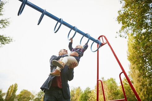 Father helping daughter on monkey bars in playground - CUF08503