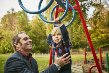 Father helping daughter on monkey bars in playground - CUF08504