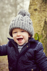 Portrait of male toddler in knitted hat in forest - CUF08511