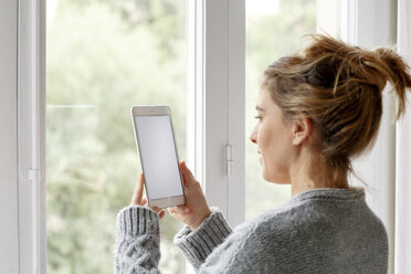 Frau zu Hause, am Fenster stehend, mit digitalem Tablet - CUF08570