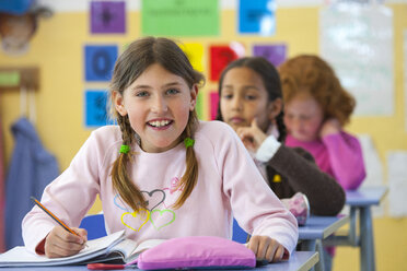 Portrait of primary schoolgirl writing in classroom - CUF08582