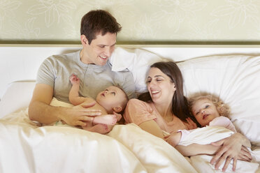 Kleines Mädchen und kleine Schwester kuscheln mit ihren Eltern im Bett - CUF08605