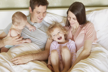 Female toddler and baby sister in bed with parents - CUF08608