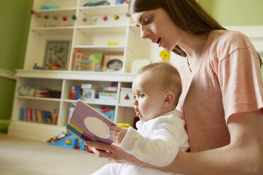 Mid erwachsene Frau und Baby Tochter lesen Märchenbuch im Spielzimmer - CUF08613