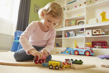 Female toddler playing with toy train on playroom floor - CUF08616
