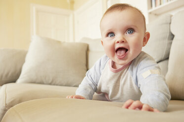 Portrait of cute blue eyed baby girl on sofa - CUF08617