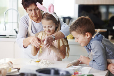 Großmutter hilft Mädchen beim Osterbacken am Küchentisch - CUF08652