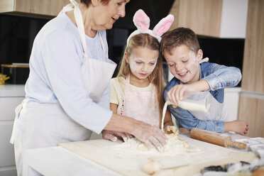 Mädchen und Bruder helfen Großmutter beim Osterbacken am Küchentisch - CUF08653