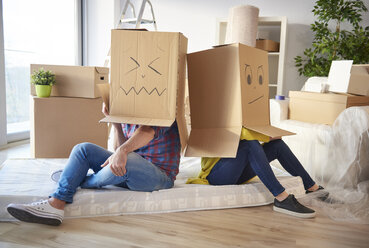 Young couple at home, wearing cardboard boxes on heads, faces drawn on boxes - CUF08665