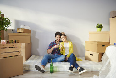 Young couple at home, surrounded by cardboard boxes, drinking champagne - CUF08666