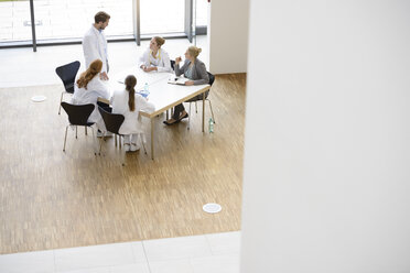 Gruppe von Ärzten, die an einem Tisch sitzen und eine Besprechung abhalten, Blick von oben - CUF08678