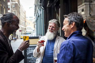 Drei reife Männer, die vor einer Kneipe stehen, Biergläser halten und lachen - CUF08688
